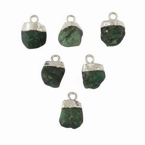 May include: Six emerald green gemstone pendants with silver settings. Each pendant features a rough, natural-looking emerald stone.