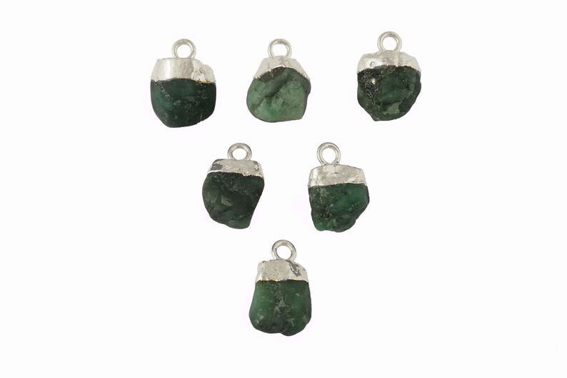 May include: Six emerald green gemstone pendants with silver settings. Each pendant features a rough, natural-looking emerald stone.