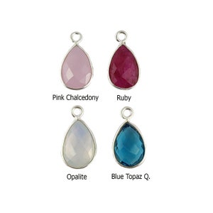 Può includere: Quattro ciondoli a forma di goccia di pietra preziosa con montature in argento. Le pietre preziose sono calcedonio rosa, rubino, opale e topazio blu.