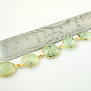 May include: A gold chain bracelet with green gemstone beads. The bracelet is measured against a ruler, showing the beads are approximately 1 inch in size.