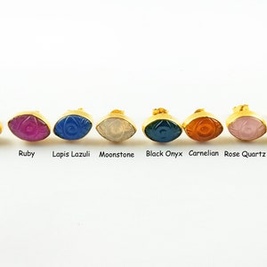 Peut inclure: Huit paires de boucles d'oreilles dorées avec un motif d'œil maléfique. Chaque paire présente une pierre précieuse différente : labradorite, rubis, lapis-lazuli, pierre de lune, onyx noir, cornaline, quartz rose et turquoise.