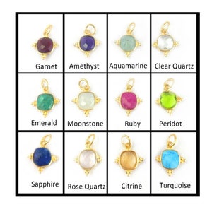 May include: Twelve gold charms with different colored gemstones. Each charm features a square gemstone with a gold frame and four gold accents. The gemstones are: Garnet, Amethyst, Aquamarine, Clear Quartz, Emerald, Moonstone, Ruby, Peridot, Sapphire, Rose Quartz, Citrine, and Turquoise.