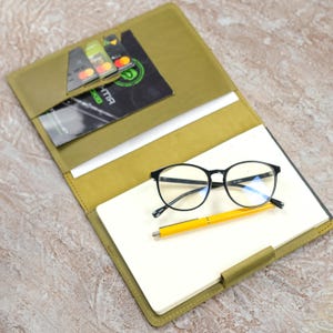 Estojo de couro para bloco de notas com capa superior, bolso para papel, porta-caneta e 3 compartimentos para cartões.