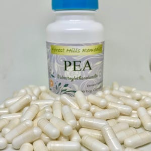 May include: A white bottle with a blue lid labelled "Forest Hills Remedies PEA Palmitoylethanolamide Dietary Supplement 60 Veg Caps" and a pile of white capsules.