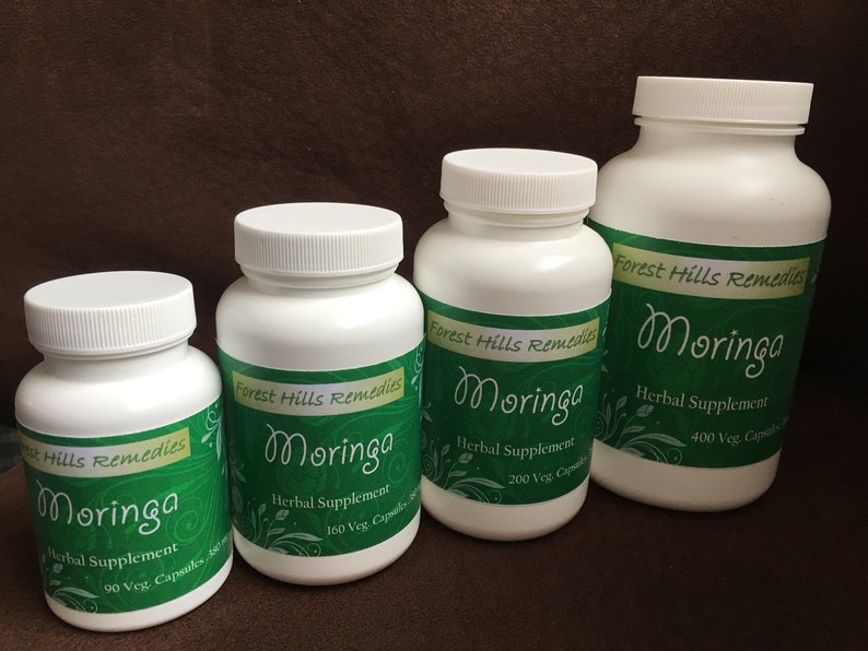 May include: Four white bottles of Moringa herbal supplement, labeled with green and white text. The bottles are arranged in a row from largest to smallest, with the largest bottle on the right. The bottles contain 400, 200, 160, and 90 vegetarian capsules.
