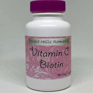 May include: A white supplement bottle with a purple cap. The label reads "Vitamin C Biotin" and "Forest Hills Remedies". The bottle contains 90 vegetarian capsules.