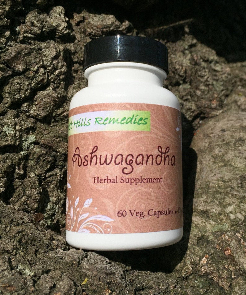 May include: White bottle with a black lid labeled "Ashwagandha Herbal Supplement" with a brown background and white floral design. The bottle contains 60 vegetarian capsules.