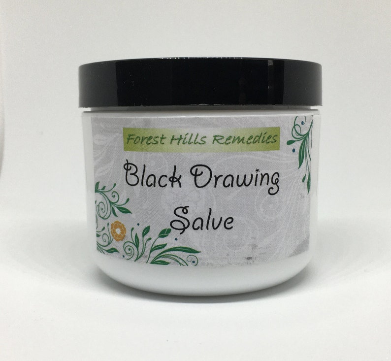 May include: A white jar with a black lid, labeled "Forest Hills Remedies Black Drawing Salve". The label has a floral design with green leaves and yellow flowers.