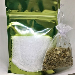 May include: A green resealable pouch with a white drawstring bag inside. The pouch contains white crystals and the bag contains dried herbs.