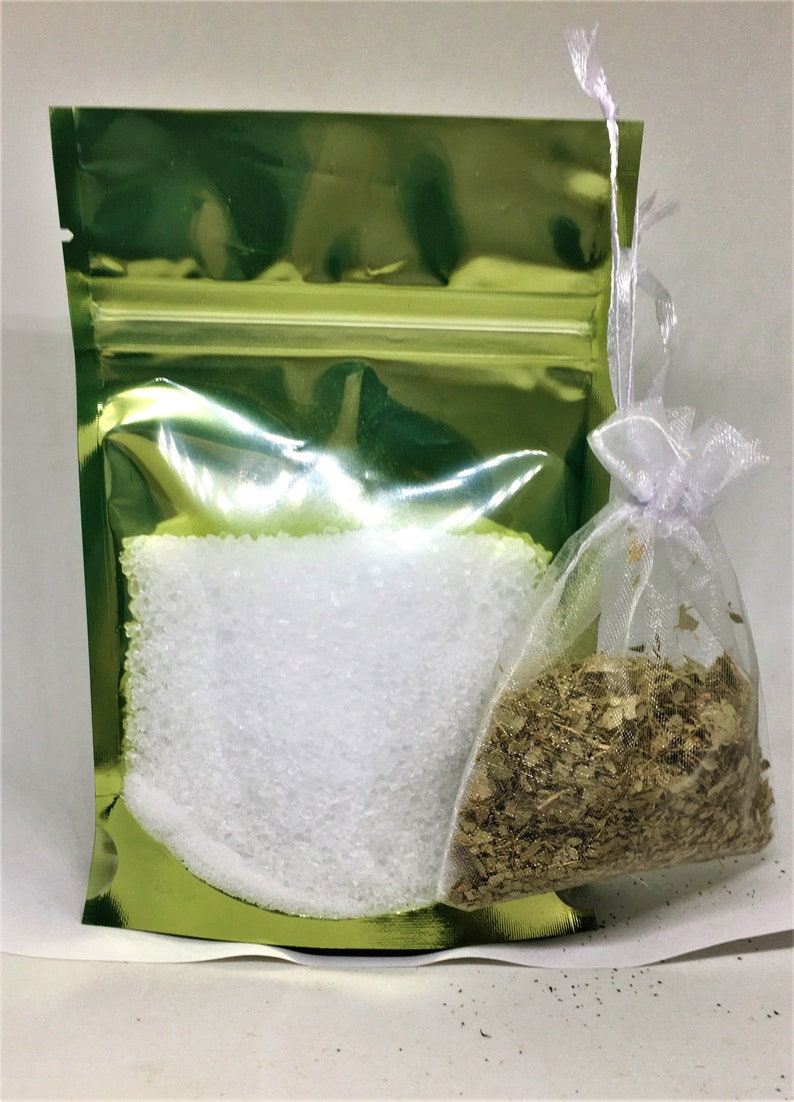 May include: A green resealable pouch with a white drawstring bag inside. The pouch contains white crystals and the bag contains dried herbs.