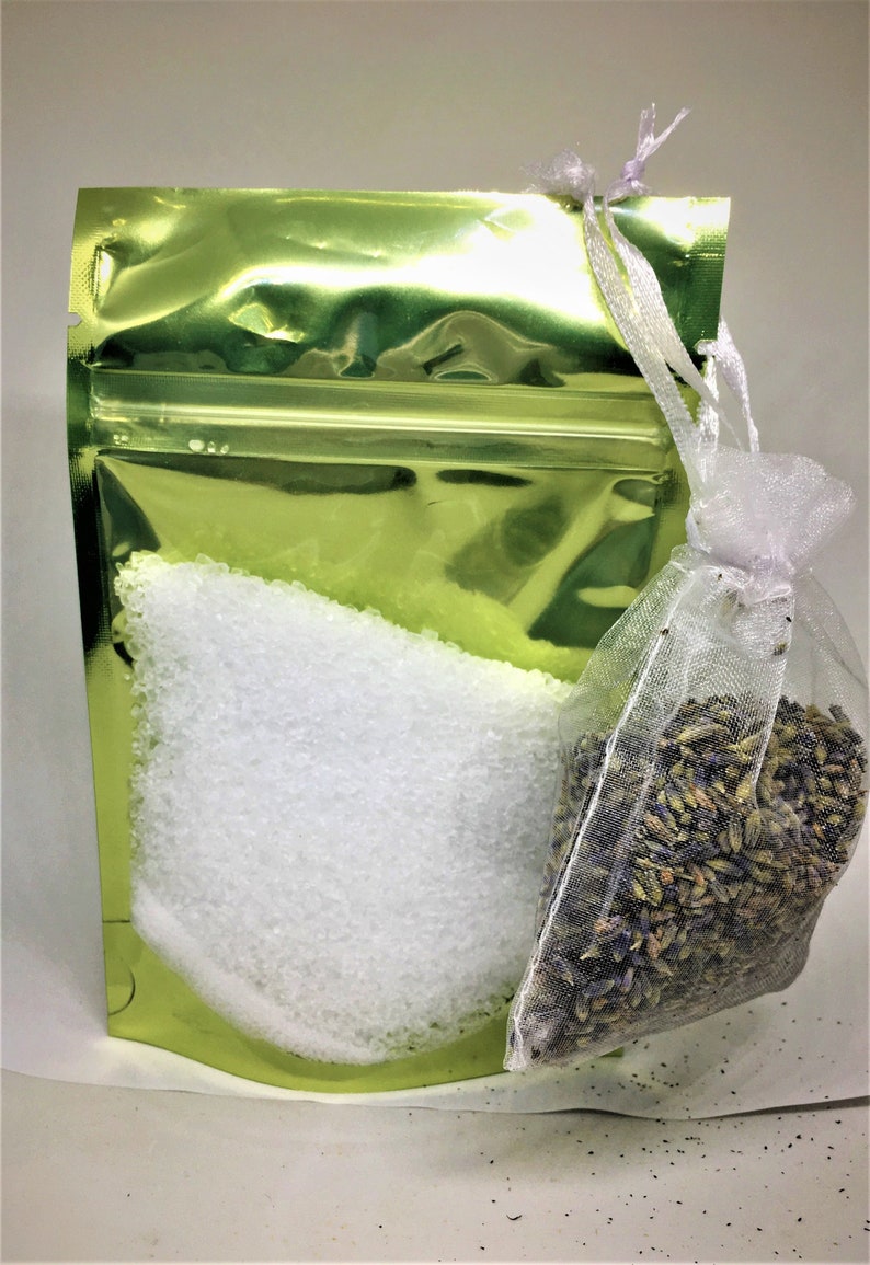 May include: A green foil pouch with a zipper closure contains white bath salts. A white mesh bag filled with dried lavender flowers is attached to the pouch.