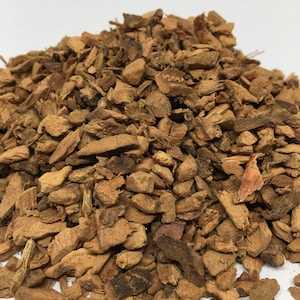 May include: A pile of dried, brown, and slightly reddish-brown bark chips. The bark is broken into irregular pieces of various sizes.