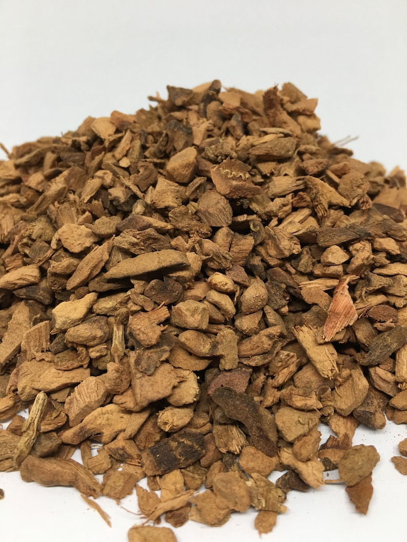 May include: A pile of dried, brown, and slightly reddish-brown bark chips. The bark is broken into irregular pieces of various sizes.