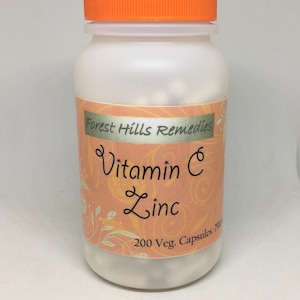 May include: A white plastic bottle with an orange lid containing white capsules. The label reads "Forest Hills Remedies Vitamin C Zinc 200 Veg. Capsules 750mg".