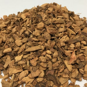 May include: A close-up of a pile of dried, brown, and slightly reddish-brown bark chips. The chips are irregularly shaped and range in size from small to medium.
