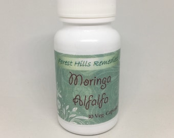 Può includere: Bottiglia bianca con un'etichetta verde che dice "Forest Hills Remedies Moringa Alfalfa 30 Veg. Capsules".