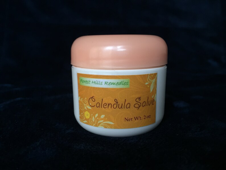 May include: A white jar with a peach-coloured lid, labelled "Forest Hills Remedies Calendula Salve Net Wt. 2 oz."