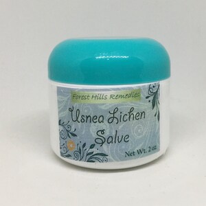 May include: A white jar with a teal lid, labelled "Forest Hills Remedies Usnea Lichen Salve" with a floral design and "Net Wt. 2 oz".