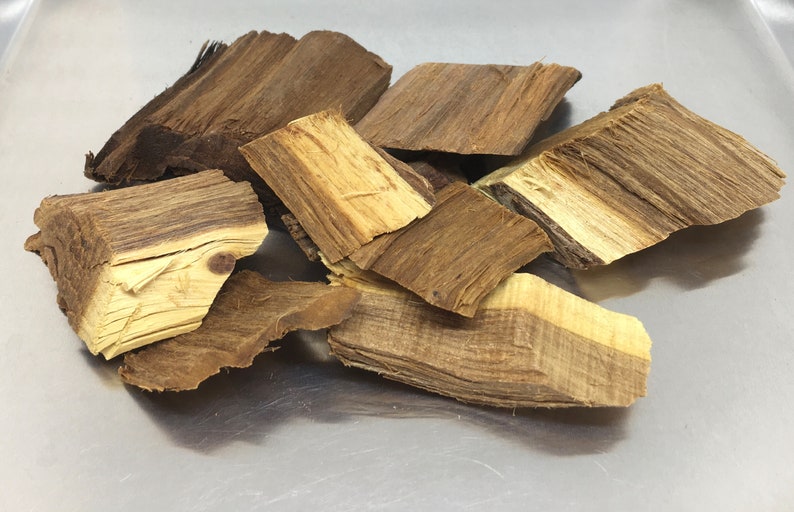 May include: A pile of brown and light brown wood chips. The chips are irregularly shaped and have a rough texture.