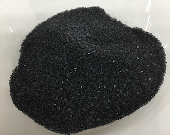 May include: A close-up of a pile of black salt crystals.