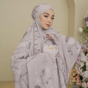 May include: A light purple prayer garment set with a matching head covering and small handbag. The set features a floral pattern and lace trim. The handbag has a gold-coloured accent. The "UMMA COLLECTION" logo is visible in the bottom right corner.