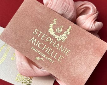 Puede incluir: Tarjetas de visita de terciopelo rosa con letras doradas. Las tarjetas muestran el nombre "Stephanie Michelle Photography" y un diseño floral. Se presentan sobre una superficie roja con tela rosa.