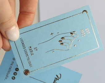 Puede incluir: Tarjeta de visita azul con letras en relieve dorado y una mano con uñas arregladas. El texto dice "Maria, Cosmetóloga Licenciada, Por, Est 2022".