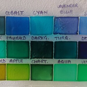 May include: A color chart with 16 paint swatches labeled with names like Indigo, Cobalt, Cyan, Lavender Blue, Sky, Lagoon, Emerald, Darkg. Turq., Deep, Greengold, Apple, Chart., Aqua, and Vivid.