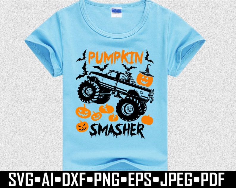 May include: Light blue t-shirt with a Halloween-themed graphic. The design features a monster truck with the text "PUMPKIN SMASHER", pumpkins, and bats. The shirt is made of a soft material.