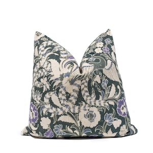 Op de afbeelding: Decoratief sierkussen met een donkergroene achtergrond en een bloemenpatroon in crème, paars en blauw. Het ontwerp bevat gestileerde bloemen, bladeren en een vogelmotief, wat een vintage esthetiek creëert.