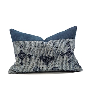 Op de afbeelding: Een rechthoekig decoratief kussen met een blauwe bovenkant en een patroon. Het kussen heeft een lichtblauw en wit patroon met donkerblauwe ruit- en bloemvormen. Het kussen staat op een witte achtergrond.