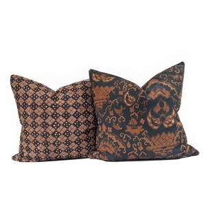May include: Two decorative throw pillows with patterned fabric. One pillow features a brown and black geometric design. The other pillow has a dark blue background with a brown, ornate pattern. Both pillows are square-shaped.