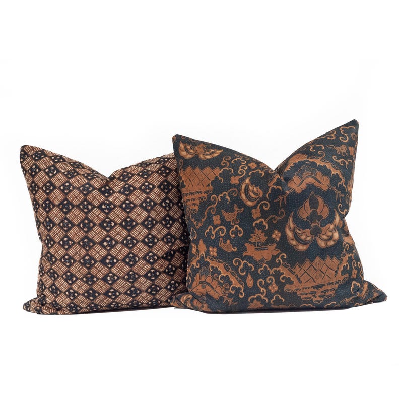 May include: Two decorative throw pillows with patterned fabric. One pillow features a brown and black geometric design. The other pillow has a dark blue background with a brown, ornate pattern. Both pillows are square-shaped.