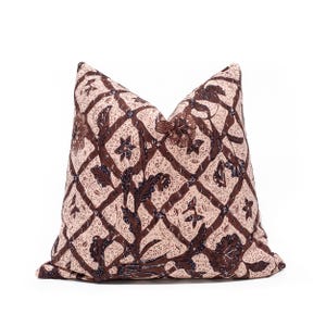 Peut inclure: Un coussin carré doté d'une base de couleur crème avec un motif en treillis marron foncé. Le design présente des motifs floraux et végétaux complexes à l'intérieur de chaque losange, accentués par de petites textures pointillées.
