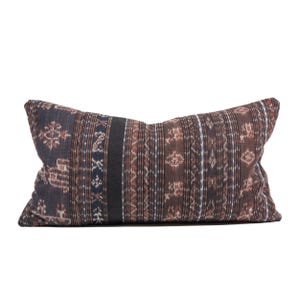 Op de afbeelding: Een lang, rechthoekig kussen met een bruin, zwart en blauw geometrisch patroon. Het kussen is gemaakt van een zachte, geweven stof.