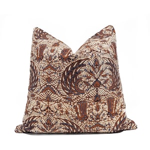 Op de afbeelding: Een vierkant kussen met een crèmekleurige achtergrond en een bruin en marineblauw batikpatroon. Het patroon bevat bloem- en abstracte vormen. Het kussen heeft een zachte, getextureerde uitstraling met een gedetailleerd ontwerp.