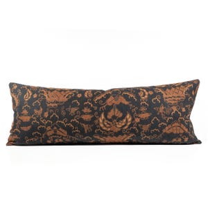 May include: A long, rectangular cushion with a dark blue background and a brown patterned design. The pattern features stylised flowers, birds, and clouds.