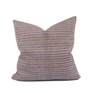 Op de afbeelding: Een gestreept kussen met een kleurpatroon in paars, blauw en rood. Het kussen is gemaakt van een zachte, geweven stof.