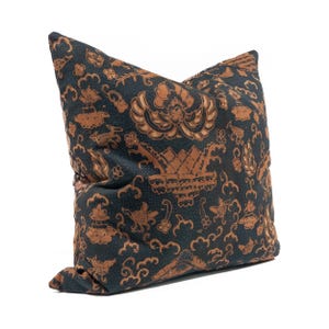 May include: Decorative throw pillow with a dark teal background and a repeating pattern in shades of brown. The pattern includes floral and geometric shapes. The pillow is square and has a soft, textured appearance.