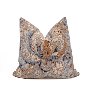 Può includere: Un cuscino quadrato caratterizzato da una stampa dettagliata in stile batik con un motivo ripetitivo di uccelli stilizzati e disegni floreali. La palette di colori è composta da blu navy profondo, marrone chiaro caldo e bianco sul tessuto.