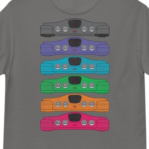 May include: A gray t-shirt with a stack of six colorful Nintendo 64 game consoles printed on the front. The consoles are stacked vertically, with the top console being gray, followed by purple, blue, green, orange, and pink.