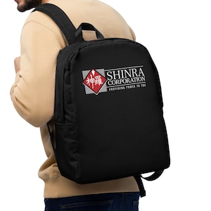 Może przedstawiać: Czarny plecak z białym logo, na którym widnieje napis "Shinra Corporation" i "Providing Power to You". Logo zawiera również czerwony diament z japońskimi znakami.