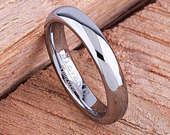 May include: A silver tungsten carbide ring with a polished finish. The ring is engraved with the words "Steven G Tungsten".