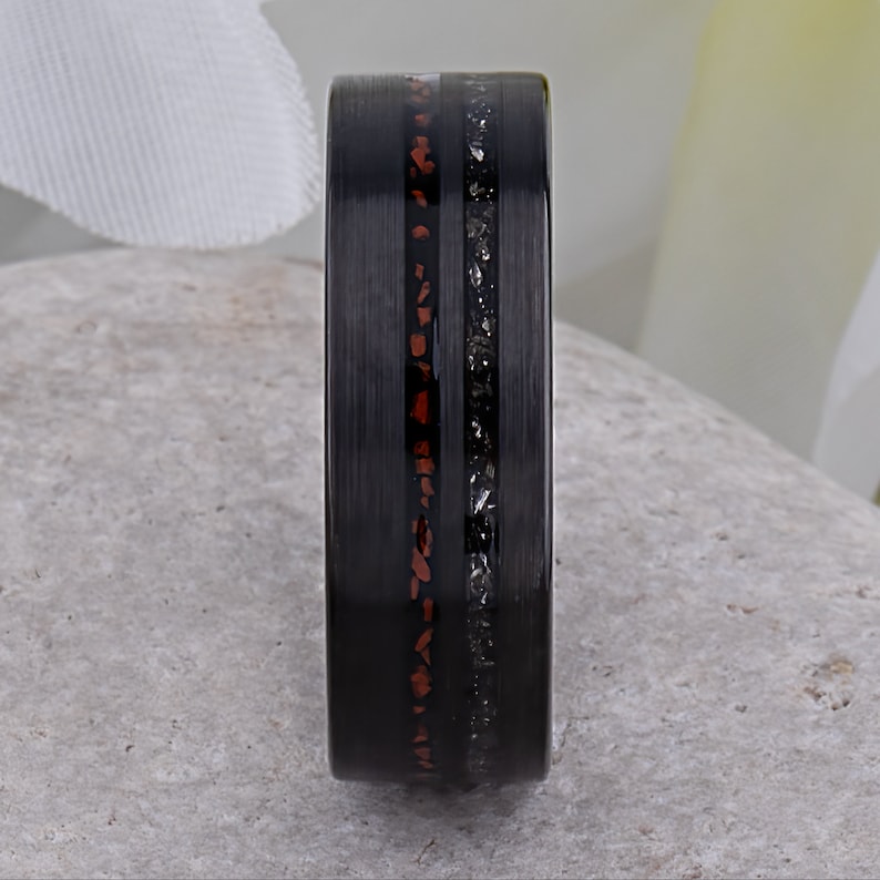 May include: A black tungsten carbide ring with a thin line of red and black inlay.