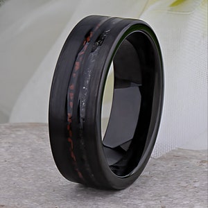 May include: A black tungsten carbide ring with a red and black inlay. The ring has a polished finish.