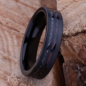 May include: A black tungsten carbide ring with a red and black inlay. The ring has a brushed finish.