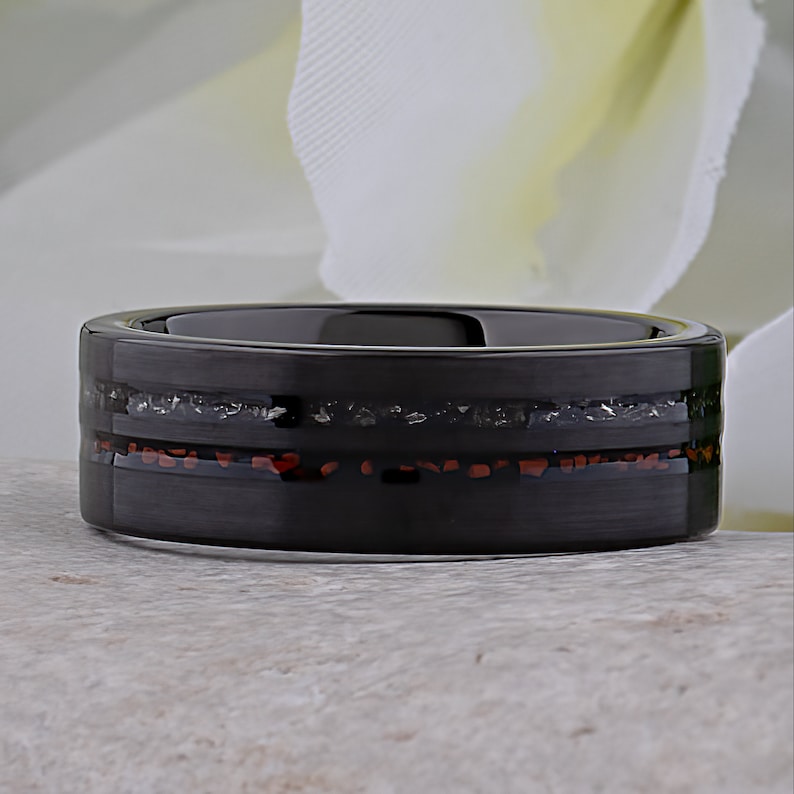May include: A black tungsten carbide ring with a thin red and silver inlay. The ring has a brushed finish.