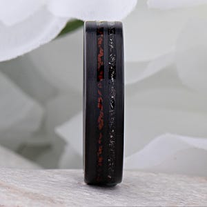 May include: A black ring with a red and silver inlay. The ring is made of a durable material and has a sleek, modern design.
