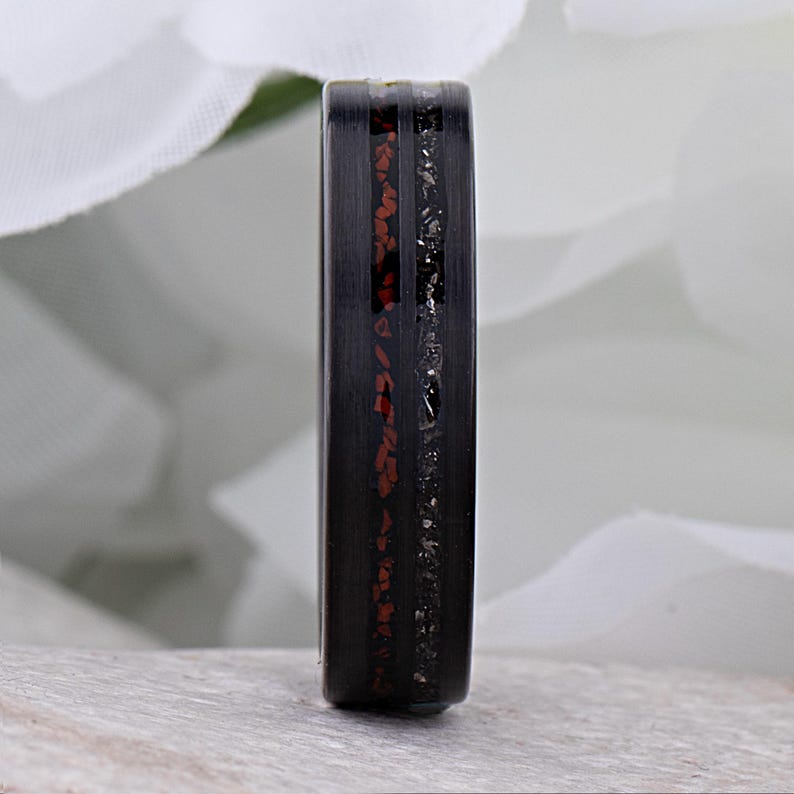 May include: A black ring with a red and silver inlay. The ring is made of a durable material and has a sleek, modern design.