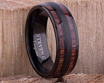 May include: Black tungsten ring with a brown wood inlay and the inscription "STEVEN G Tungsten".
